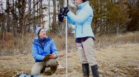 Gregg Moore and UNH graduate student Emily Dutton measure the depth of sediment in as part of their experiment in a Durham salt marsh.