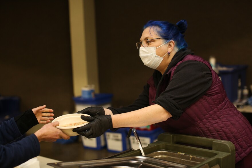 A volunteer hands someone warm soup inside a warming center.