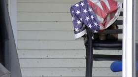 A muddy American flag is draped over a chair outside a flooded-out mobile home at a retirement community in Fort Myers, Fla., on Sunday, Oct. 8, 2022. (AP Photo/Jay Reeves)