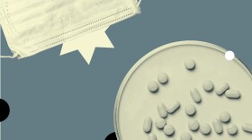 Assorted pill shapes in a dish, beside a face mask.