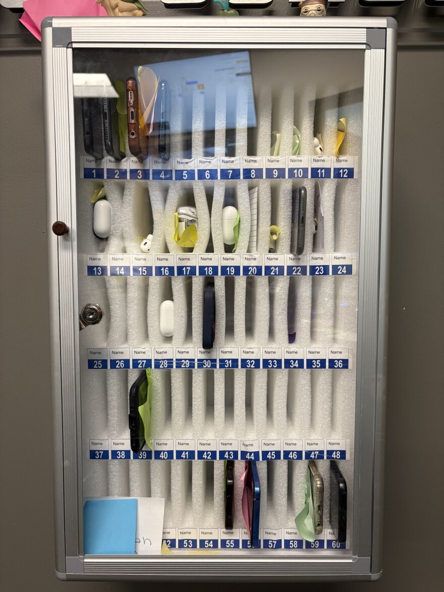 Confiscated devices sit in a case in an administrative office at Summit High School. Staff reported more than 800 phone violations this school year.