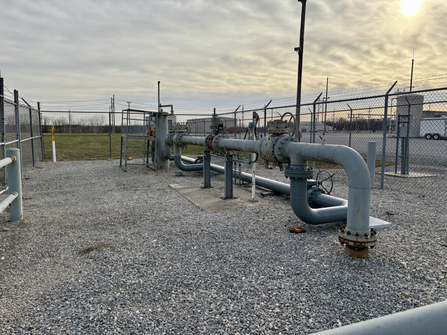 Metal pipes outside a gas plant go into the ground and connect to each other above ground. 