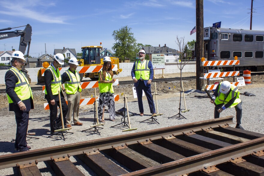 U.S. Sen. Todd Young hammers in a golden spike as part of the groundbreaking ceremony while officials, including Gov. Eric Holcomb, look on.