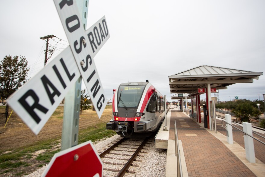 A train parked at the platform at Capital Metro's Red Line station in Leander with a railroad crossing sign in the foreground