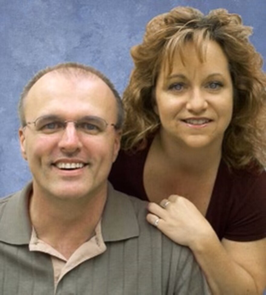 Women looking over man's shoulder as they pose for a photo