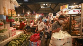 Customers, some wearing protective face masks, shop at a popular market in Managua, Nicaragua, Tuesday, April 7, 2020. Restaurants are empty, there's little traffic in the streets and beach tourists are sparse headed into Holy Week despite the government's encouragement for Nicaraguans to go about their normal lives. (AP Photo/Alfredo Zuniga)