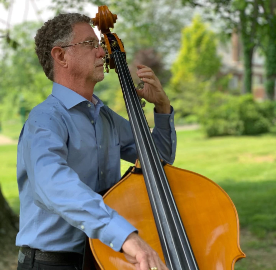 Un hombre sosteniendo el contrabajista, vestido con una camisa azul