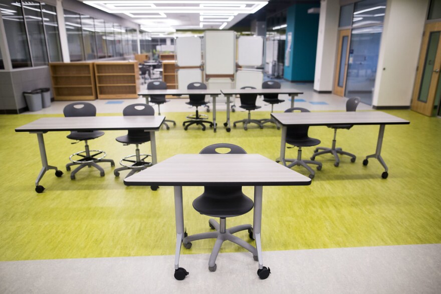 An empty classroom with desks, chairs and yellow floor.