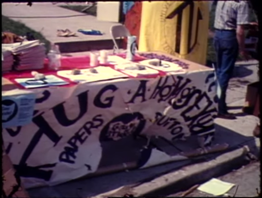 A ComFest booth with a sign that reads, Hug A Homosexual