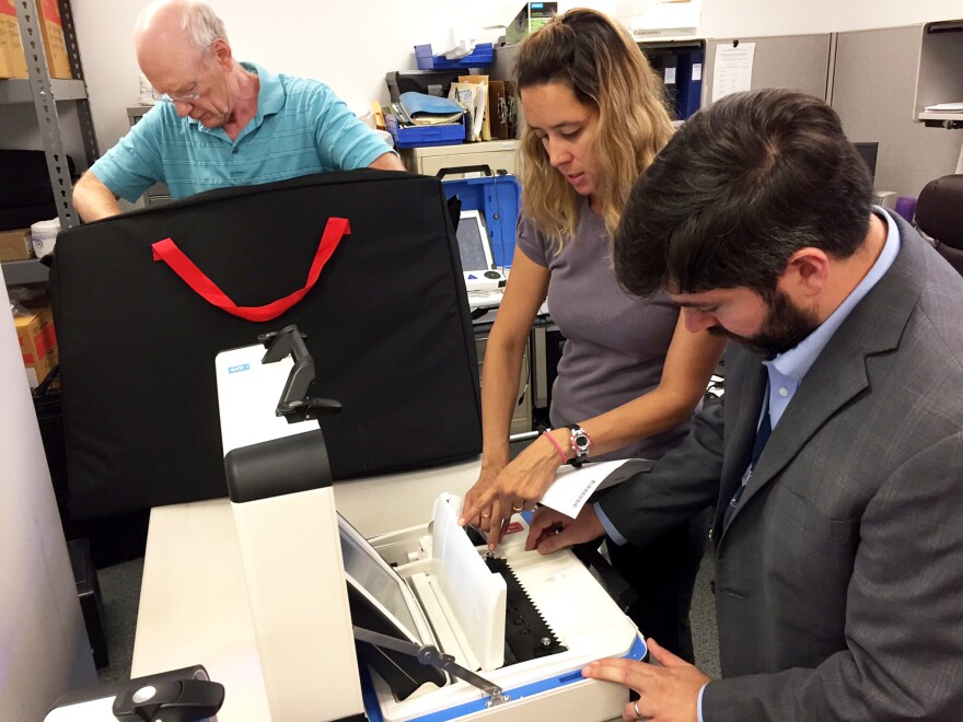 From left, Bill Wanlund of the Falls Church electoral board, Jessica Wilson of voting machine company Hart InterCivic and David Bjerke, the Falls Church director of elections test the city's new voting machines ahead of this November's election.