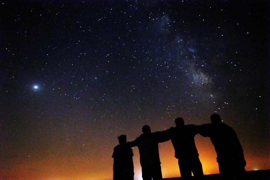 Friends look at the Milky Way galaxy rising in the night sky in Kuwait's al-Salmi desert, 120Km north of the capital, on Aug. 9, 2021. (Yasser al-Zayyat/AFP via Getty Images)