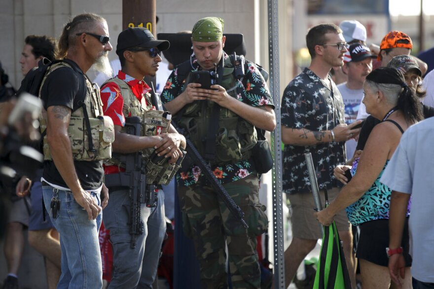Gun-carrying men wearing the Hawaiian print shirts associated with the Boogaloo movement watch a demonstration near the BOK Center where President Trump held a campaign rally in Tulsa, Okla., Saturday, June 20, 2020. 