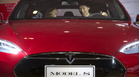 FILE - In this file photo, a man sits behind the steering wheel of a Tesla Model S electric car. Federal officials say the driver of a Tesla S sports car using the vehicle’s “autopilot” automated driving system was killed May 7 in Williston, Fla. in a collision with a truck, the first U.S. self-driving car fatality. The National Highway Traffic Safety Administration said preliminary reports indicate the crash occurred when a tractor-trailer made a left turn in front of the Tesla at a highway intersection. NHTSA said the Tesla driver died due to injuries sustained in the crash.(AP Photo/Mark Schiefelbein, File)
