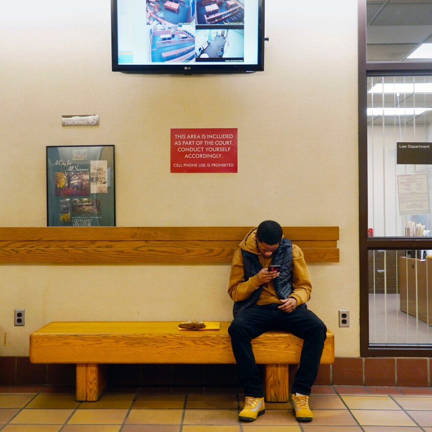 Nizer Lukerson looks at his phone while he waits to pay a fine.