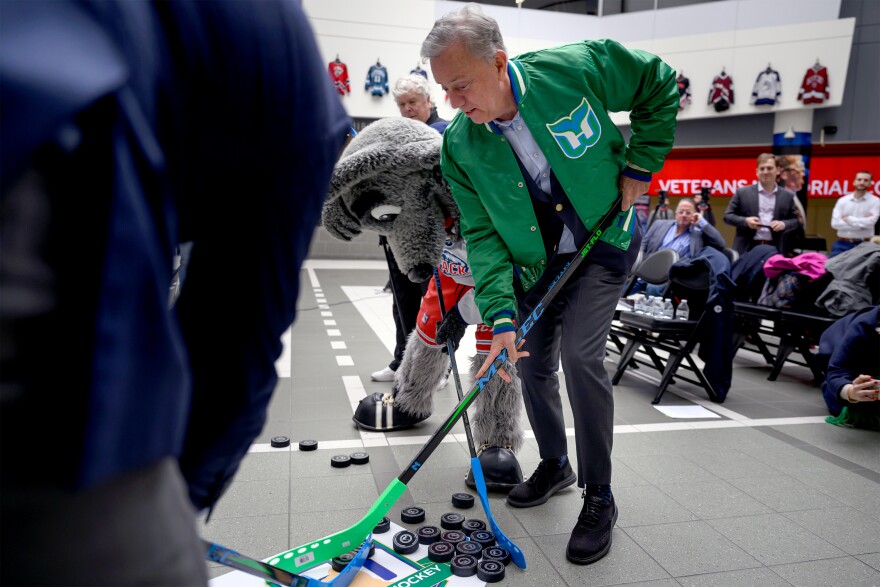 Gov. Ned Lamont competes with Hartford Mayor Arunan Arulampalam and Sonar the mascot to clear pucks off the logo for the 50th anniversary celebration of the Hartford Whalers’ founding following a press event at the XL Center on December 20, 2024.