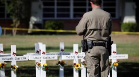 A Texas Department of Public Safety officer stands in front of crosses with the names of victims of a school shooting, at a memorial outside Robb Elementary school, two days after a gunman killed nineteen children and two adults, in Uvalde, Texas, U.S. May 26, 2022.