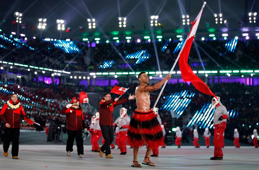 Pita Taufatofua, who competed in taekwondo in the 2016 Rio Olympics and will compete in cross-country skiing in Pyeongchang, carries the flag of Tonga during the opening ceremony.