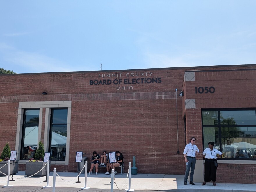 People sit and stand outside of the Summit County Board of Elections.