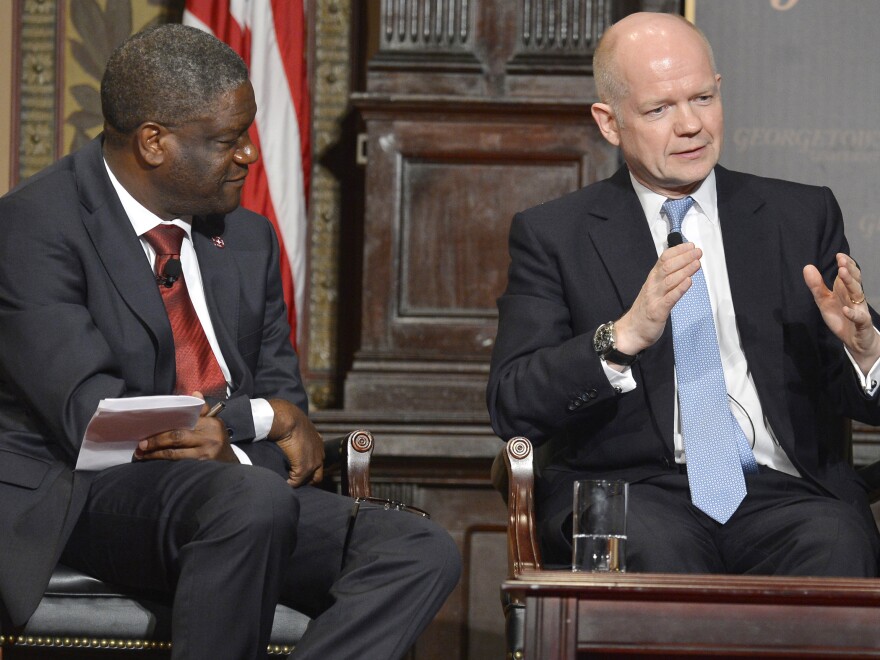 Dr. Denis Mukwege (left) listens as Britain's Foreign Secretary William Hague speaks after the two men were presented Georgetown University's annual Hillary Rodham Clinton Award for Advancing Women in Peace and Security, at Georgetown University in Washington, in February.