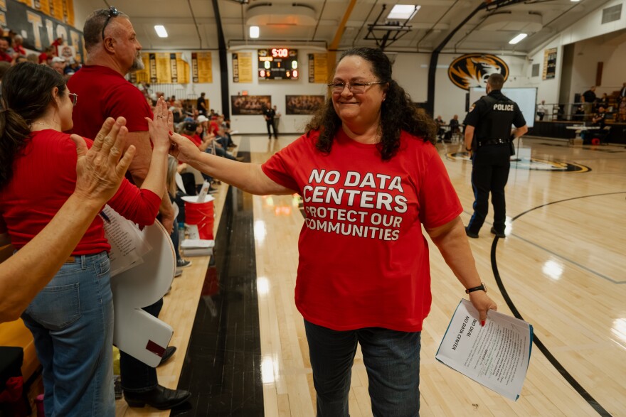 Mary Fakes high-fives fellow residents after speaking in opposition to a since-passed data center plan during a Festus City Council meeting at Festus High School on Monday.