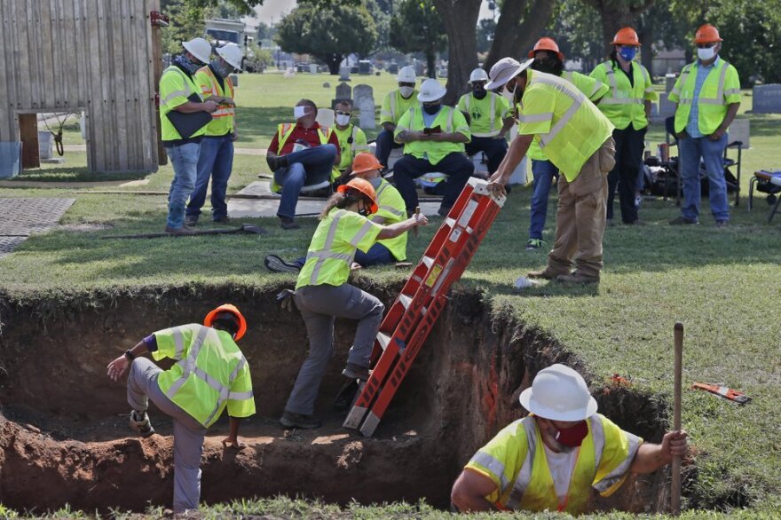 A worker climbs a ladder out of an excavation site in Tulsa's Oaklawn Cemetery.