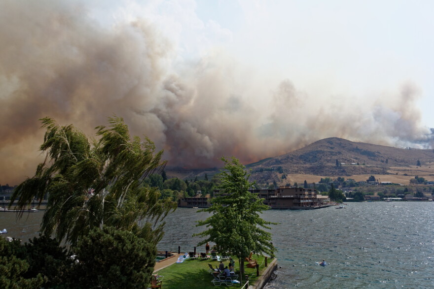 Beachgoers in Chelan watch as the wildfire comes over the butte.