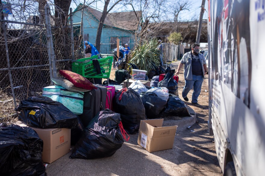 A pile of cardboard boxes, trash bags and suitcases are piled on the sidewalk just outside the entrance of Camp Rhonda. 