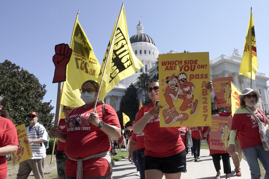 Fast food workers and their supporters hold signs as they march past the state Capitol.