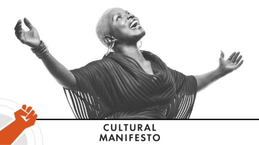 Singer-songwriter Angélique Kidjo poses and smiles for a photo in front of a white background.