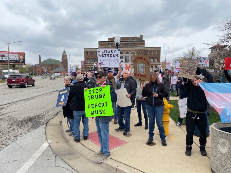 Protesters hold signs at a rally denouncing Trump Administration policies