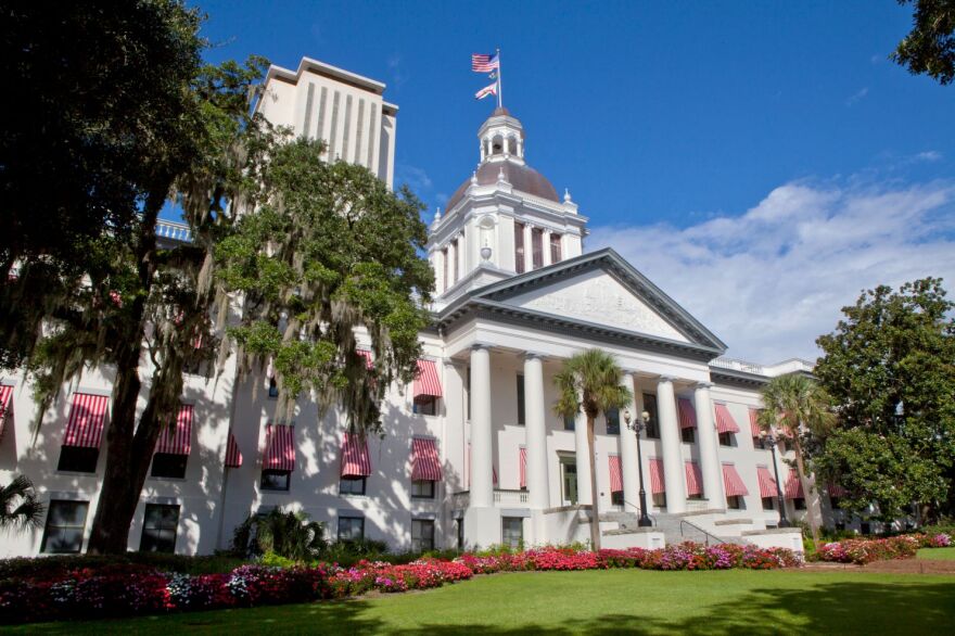 A white Capitol building with trees to the left and right