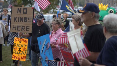 Protesters hold American flags and signs that say 'No King.'