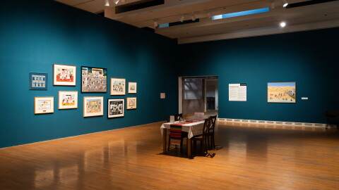 room with wood floor and blue walls, table in the middle and art hanging on the walls