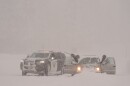 A car is stuck in and covered with snow. A California Highway Patrol vehicle is parked next to it.