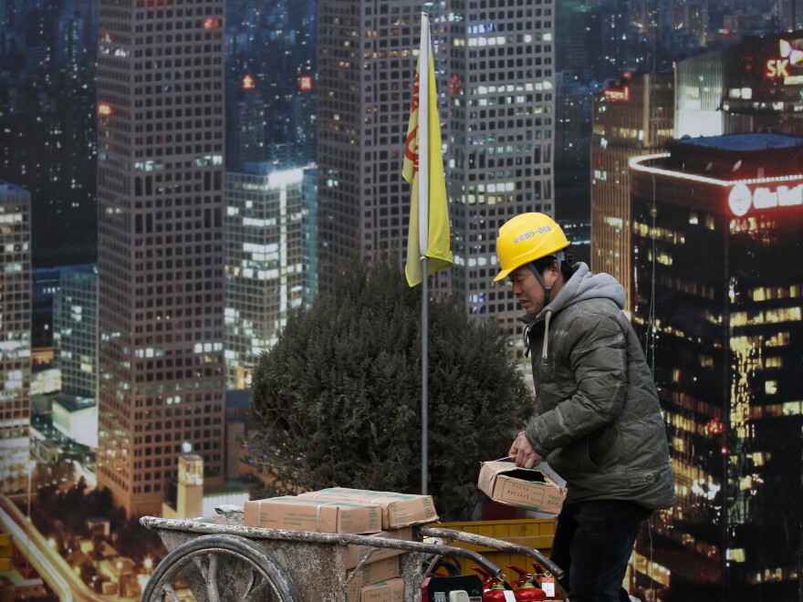 A worker loads building material on a cart outside a construction site at the Central Business District in Beijing. China's top economic planner expressed confidence this month that stronger consumer spending will help the economy grow.