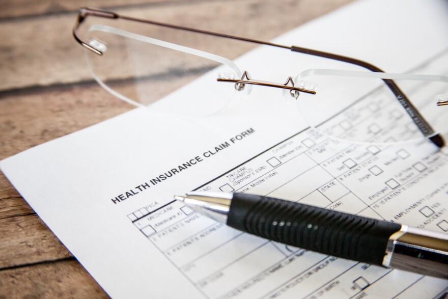 A photo of pen and glasses over health insurance forms