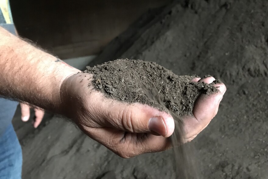 Impact Earth CEO Robert Putney holds up a handful of compost soil that has completed the almost year-long process that started out as kitchen scraps and garden refuse.