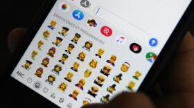 A person holds an iPhone showing emojis. (Tengku Bahar/AFP via Getty Images)