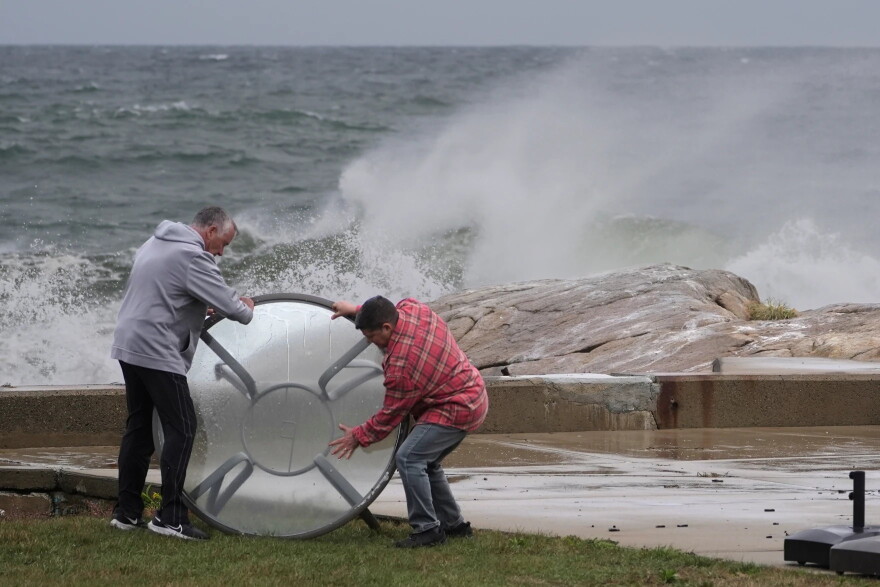 John Garrisi, left, and Gaige Graf move an outdoor table away from the shorefront during the early stages of a nor'easter storm on Friday.