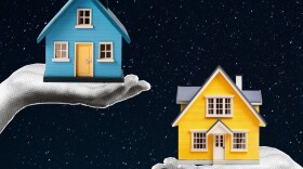 Two hands, one holding a little blue house, the other a little red house; a starry sky in the background