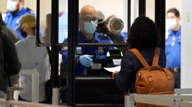In this Nov. 24, 2020 file photo, a TSA agent assist a traveler at a security checkpoint at Love Field Airport in Dallas. 