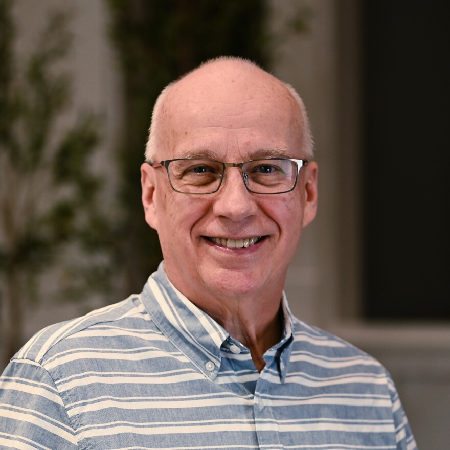 a man with glasses in a blue and white striped polo shirt