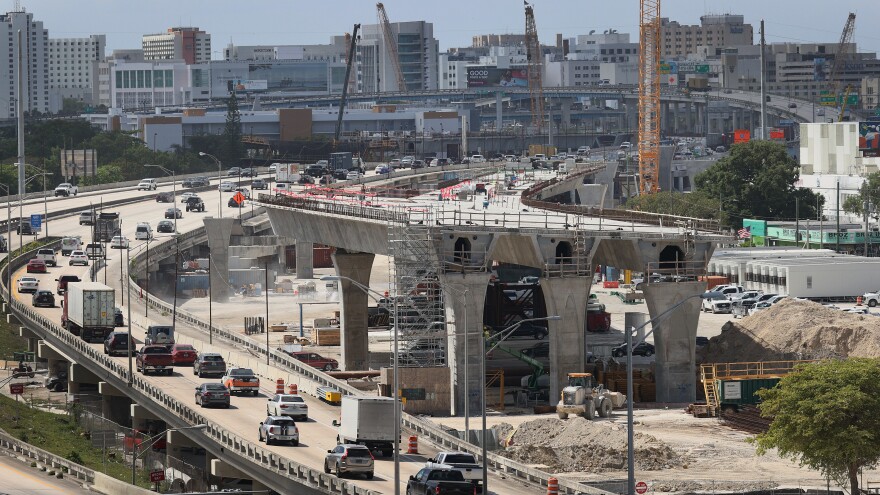 Workers improve a busy highway intersection in Miami. President Biden is proposing roughly $2 trillion to invest in the nation's infrastructure. His plan includes improvements for roads, bridges, transit, water systems, electric grids and Internet access.