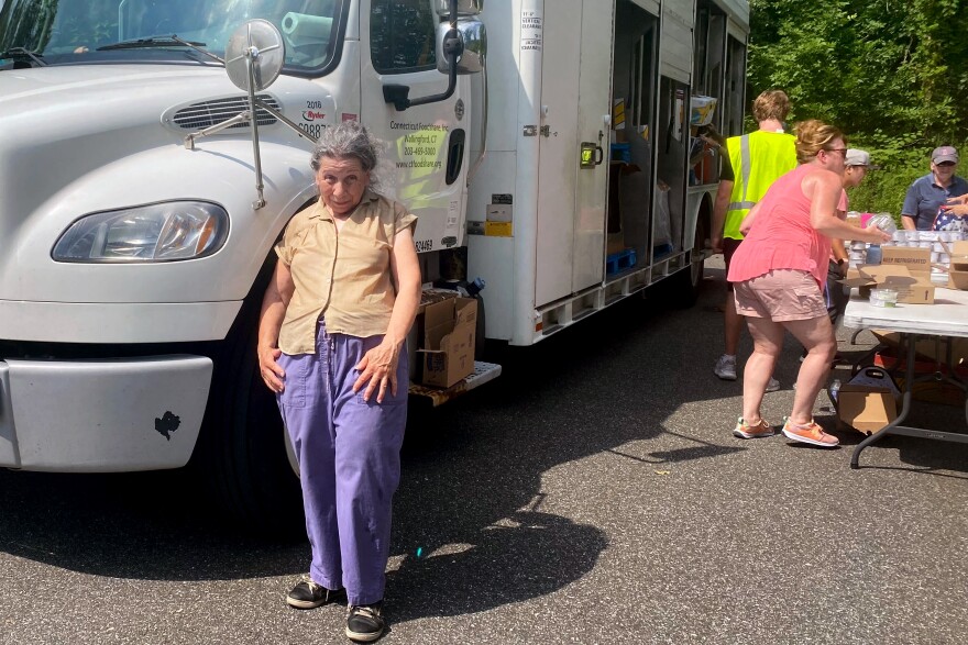 Jean Della Rocca, 66, from East Hartford, at a mobile Foodshare pantry in Glastonbury, Connecticut on July10th 2024. A high-school volunteer carried her bread and fresh veggies to her brother's car. Rocca lives with her mother and brother. She retired after a career spanning 23 years at the Hartford Institute of Living, but said despite saving money she still needs assistance for her food.