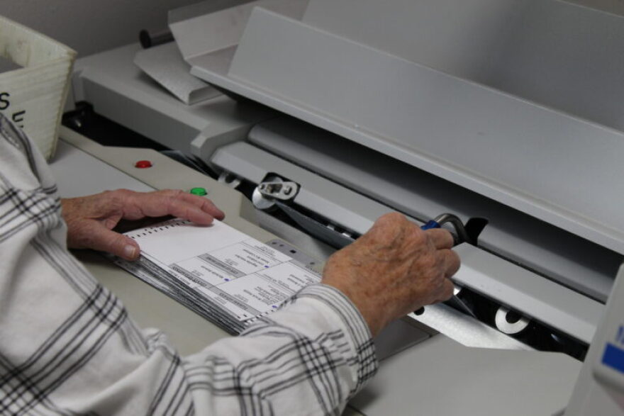 Ballots go through an extraction machine where the ballots are separated from the blue envelope.