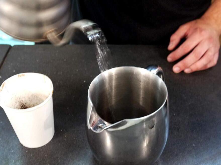 Andrew Shields, a barista at Chinatown Coffee, makes a custom cup of civet coffee, following the instructions to use a French press.