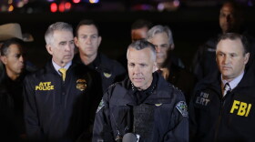 Austin Police Chief Brian Manley, center, stands with other members of law enforcement as he briefs the media, Wednesday, March 21, 2018, in the Austin suburb of Round Rock, Texas. The apparent suspect in a spate of bombing attacks that have terrorized Austin over the past month blew himself up with an explosive device as authorities closed in, the police said early Wednesday. (AP Photo/Eric Gay)