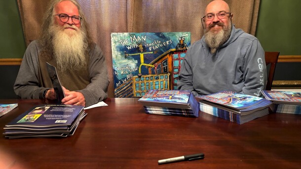 Author Rob Snow and son, Adrian Guenther (aka ARG the ARTisT) on book signing detail, with original cover painting in the background