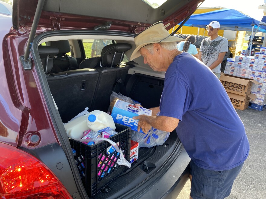 Volunteers load food in the backs of vehicles at a food distribution event at Wings of Faith Fellowship Church near Ocala.