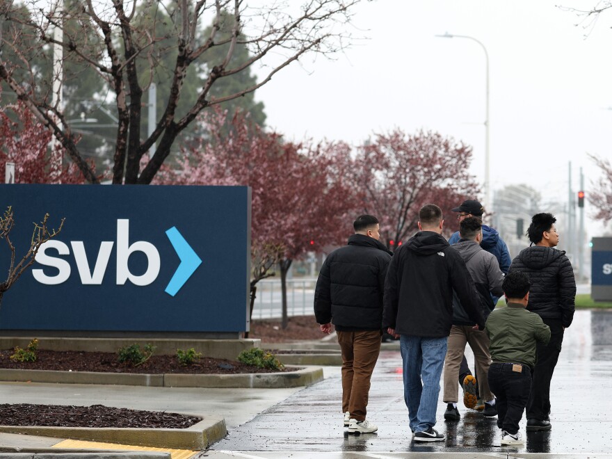 People walk through the parking lot at the Silicon Valley Bank headquarters in Santa Clara, Calif., on March 10, 2023. SVB saw a surge in deposits during the tech boom, but was forced to sell some of its bond holdings at a steep loss after seeing an increase in deposit withdrawals.